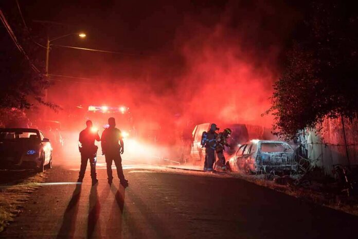shutterstock_680019202 Firefighters and police at a nighttime car fire scene
